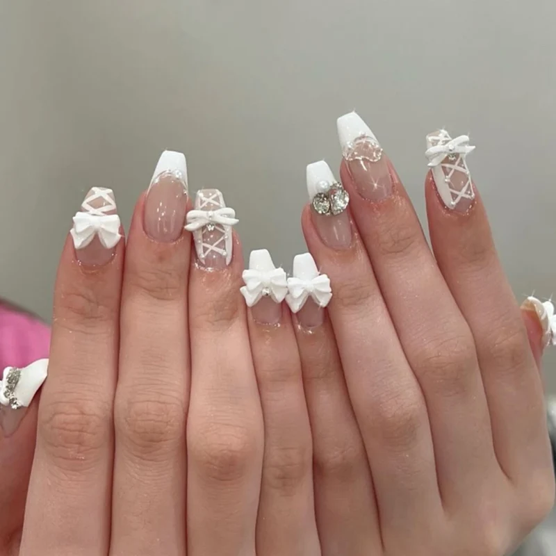 Kunstvolle Nagelkunst mit Schleifen- und Strassverzierungen Karnz