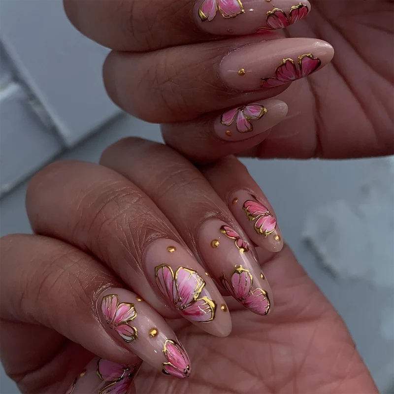 Kunstvolle Nagelkunst mit eleganten Blütenmotiven und Goldakzenten Karnz